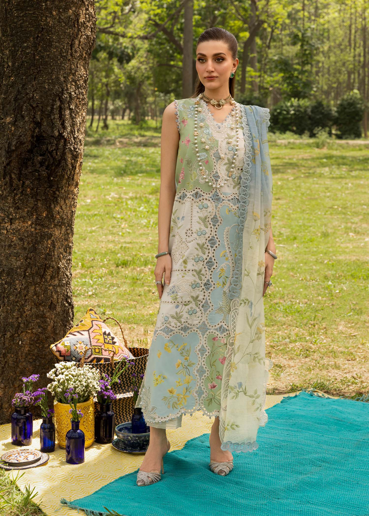 Woman in a floral dress standing outdoors with a picnic setup.