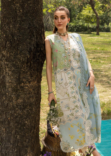 Woman in a light green embroidered dress standing next to a tree in a park.