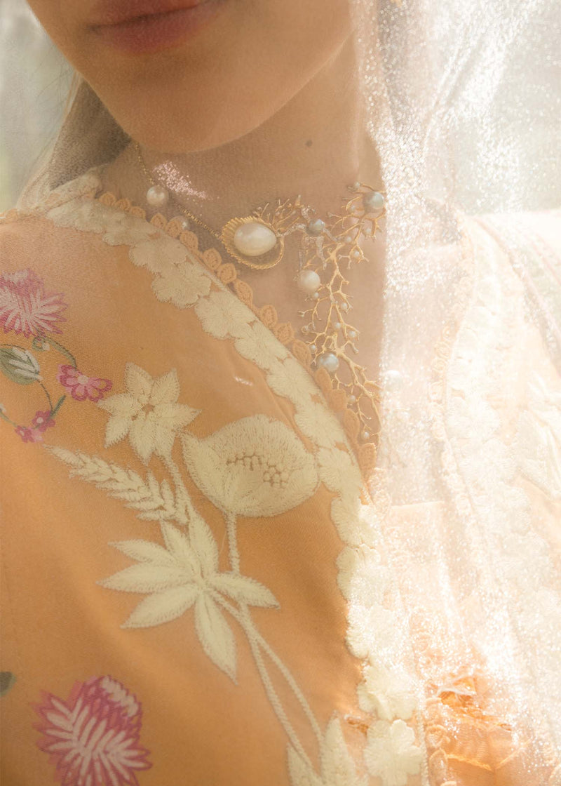 Close-up of a person wearing a floral embroidered garment with pearl accents.