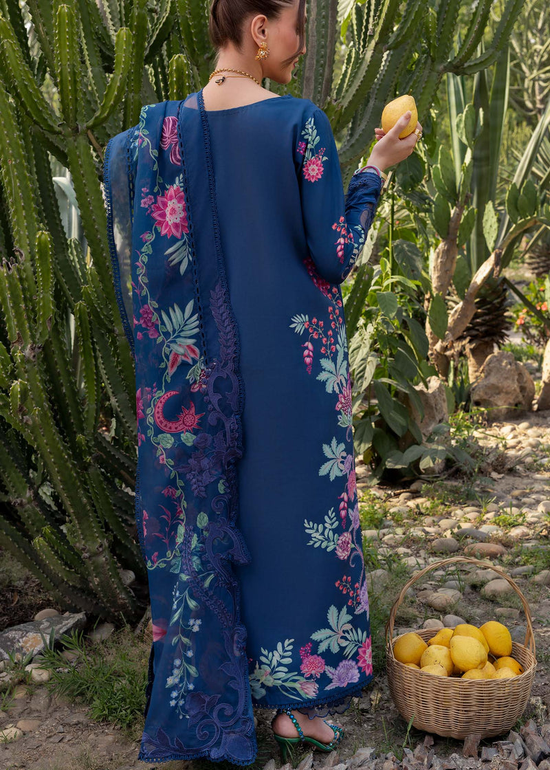 Woman in a blue floral dress holding a lemon in a cactus garden.