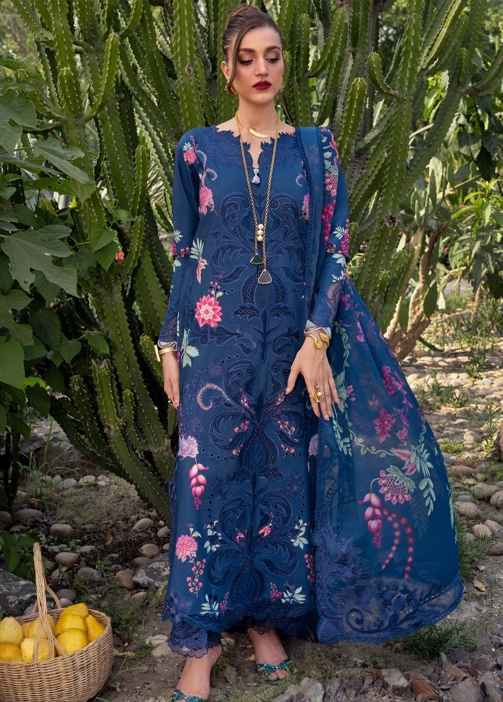 Woman in a blue embroidered dress standing in front of cacti