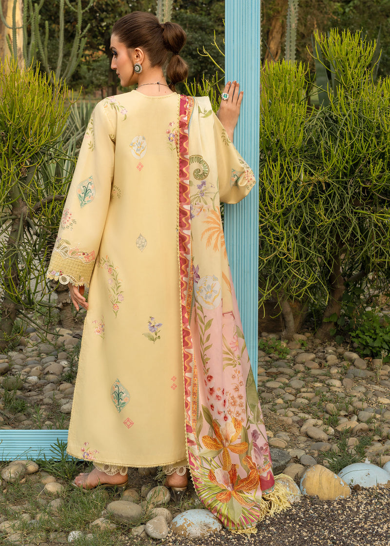 Woman wearing a light yellow embroidered dress with a colorful scarf in an outdoor setting.