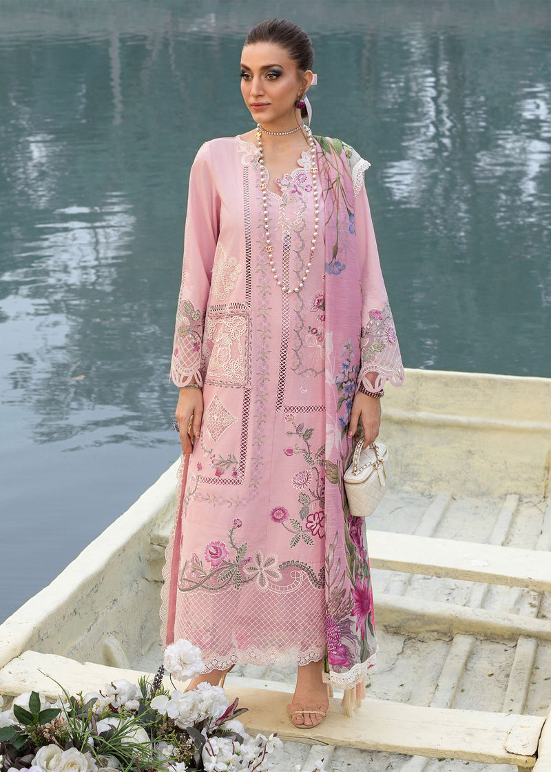 Woman in a pink embroidered outfit standing on a boat by a body of water.