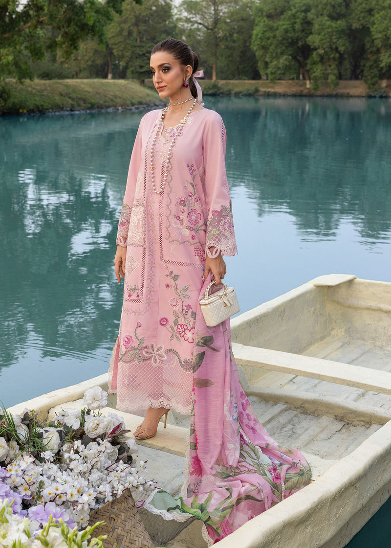 Woman in a pink embroidered outfit standing on a boat by a lake
