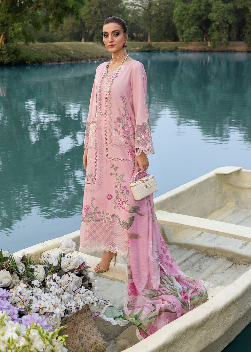 Woman in a pink embroidered outfit standing on a boat by a lake