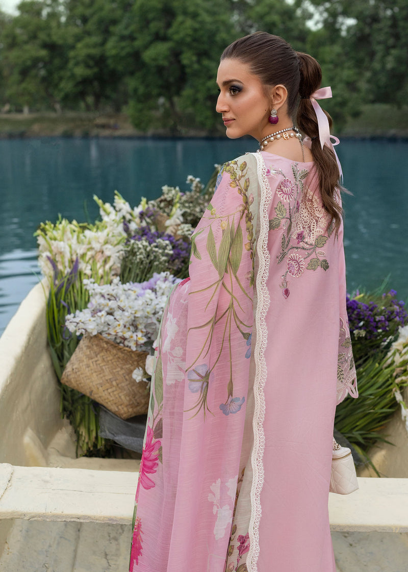 Woman in a pink embroidered outfit by a lake with flowers.