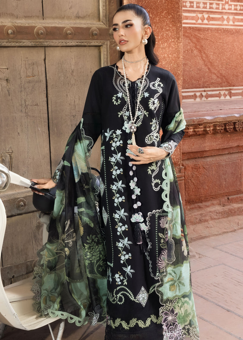 Woman in a black and green embroidered dress standing in front of a textured wall.