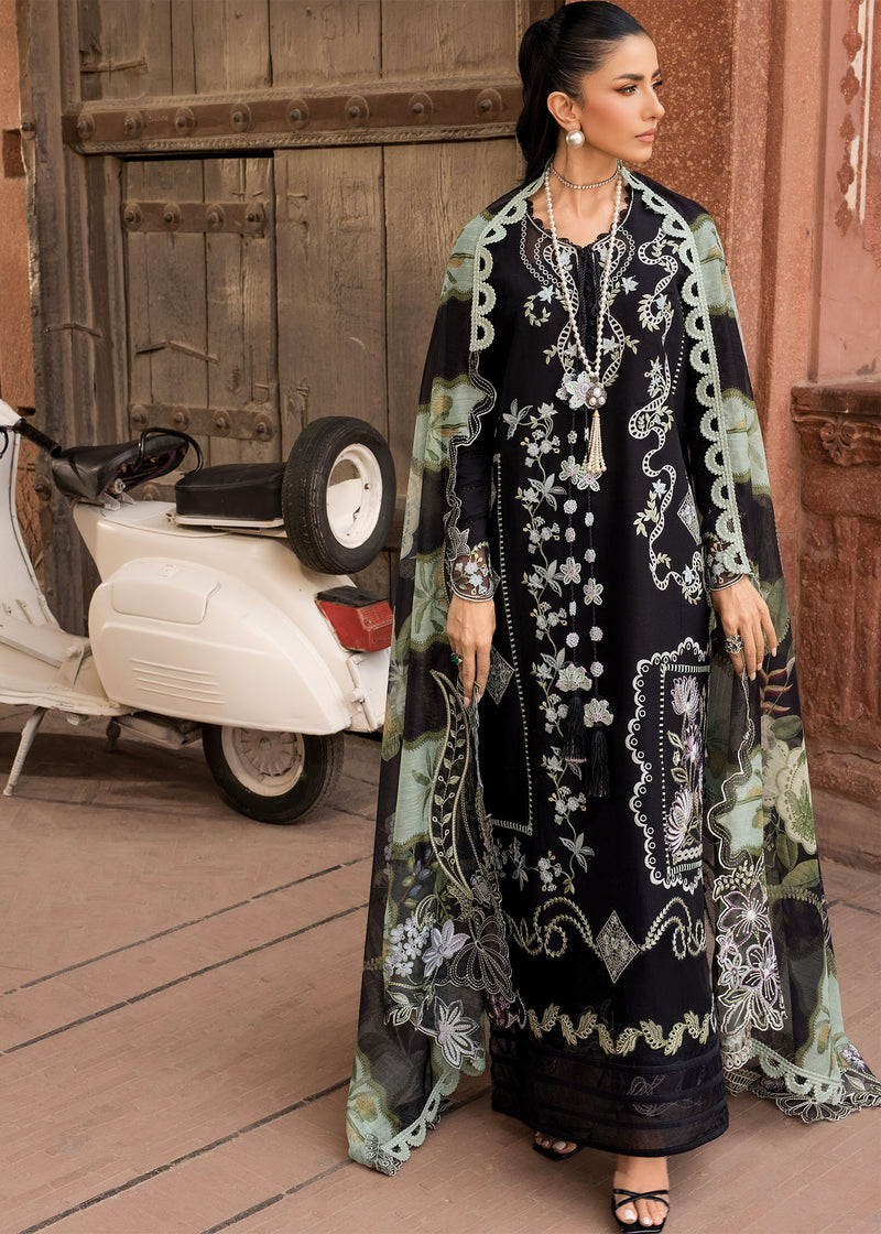 Woman in a long, dark dress with white patterns standing in front of a scooter.