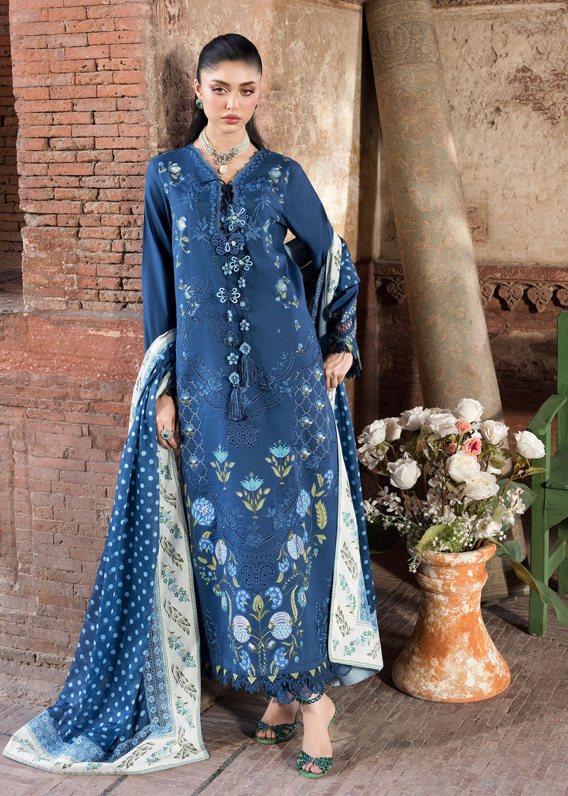 Woman in a blue embroidered dress standing in front of a brick wall with flowers.