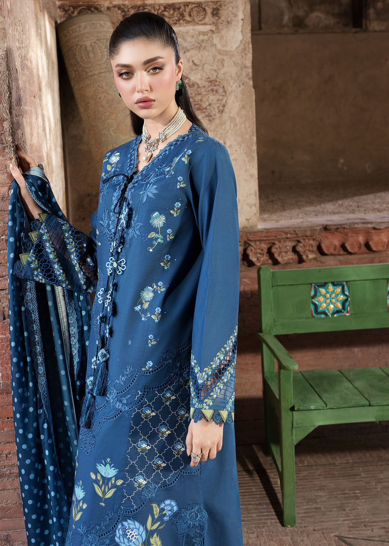 Woman in a blue floral dress standing in front of a textured wall with a green bench.