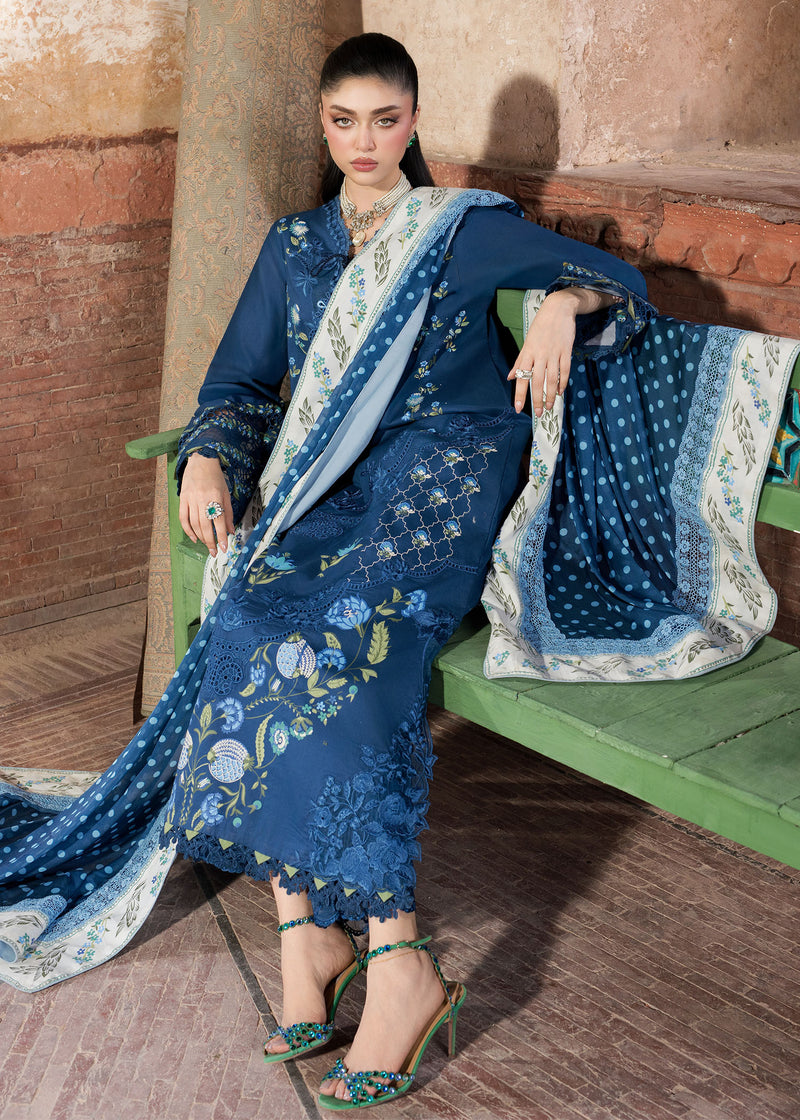 Woman in a blue embroidered outfit sitting on a bench with a patterned scarf.