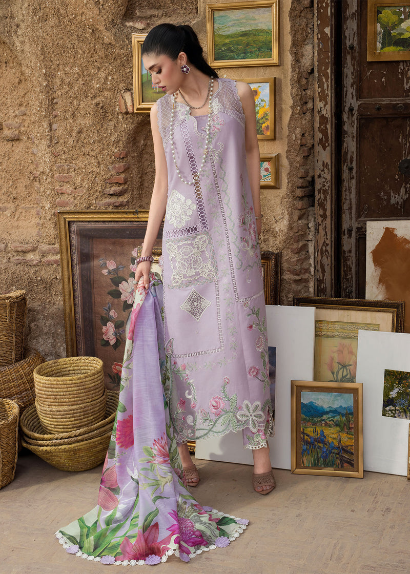 Woman in a floral dress holding a matching scarf in a rustic interior setting with framed pictures.
