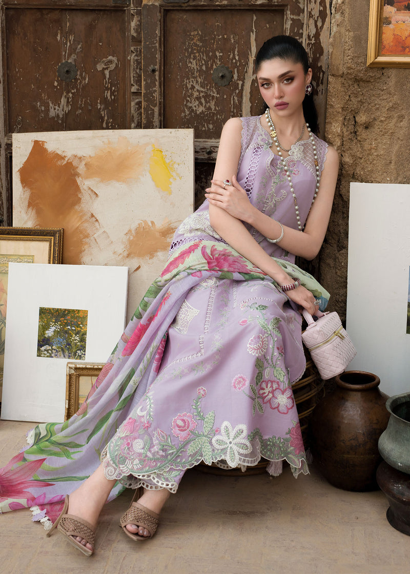 Woman in a floral dress sitting against a textured wall with artworks.