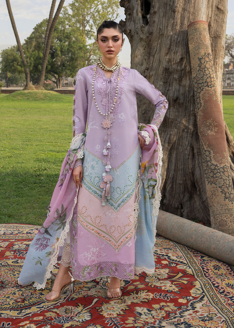 Woman in a traditional outfit with floral patterns standing in a garden.
