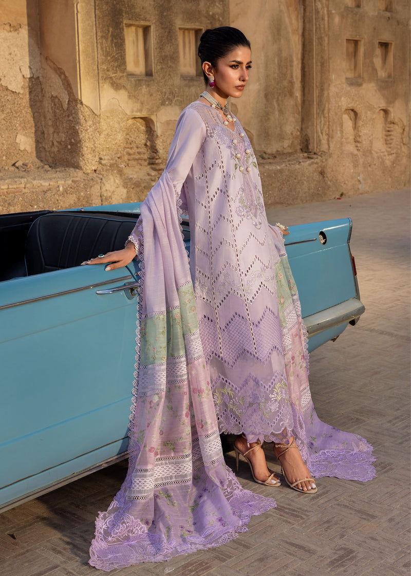 Woman in a light purple traditional outfit standing next to a vintage blue car.