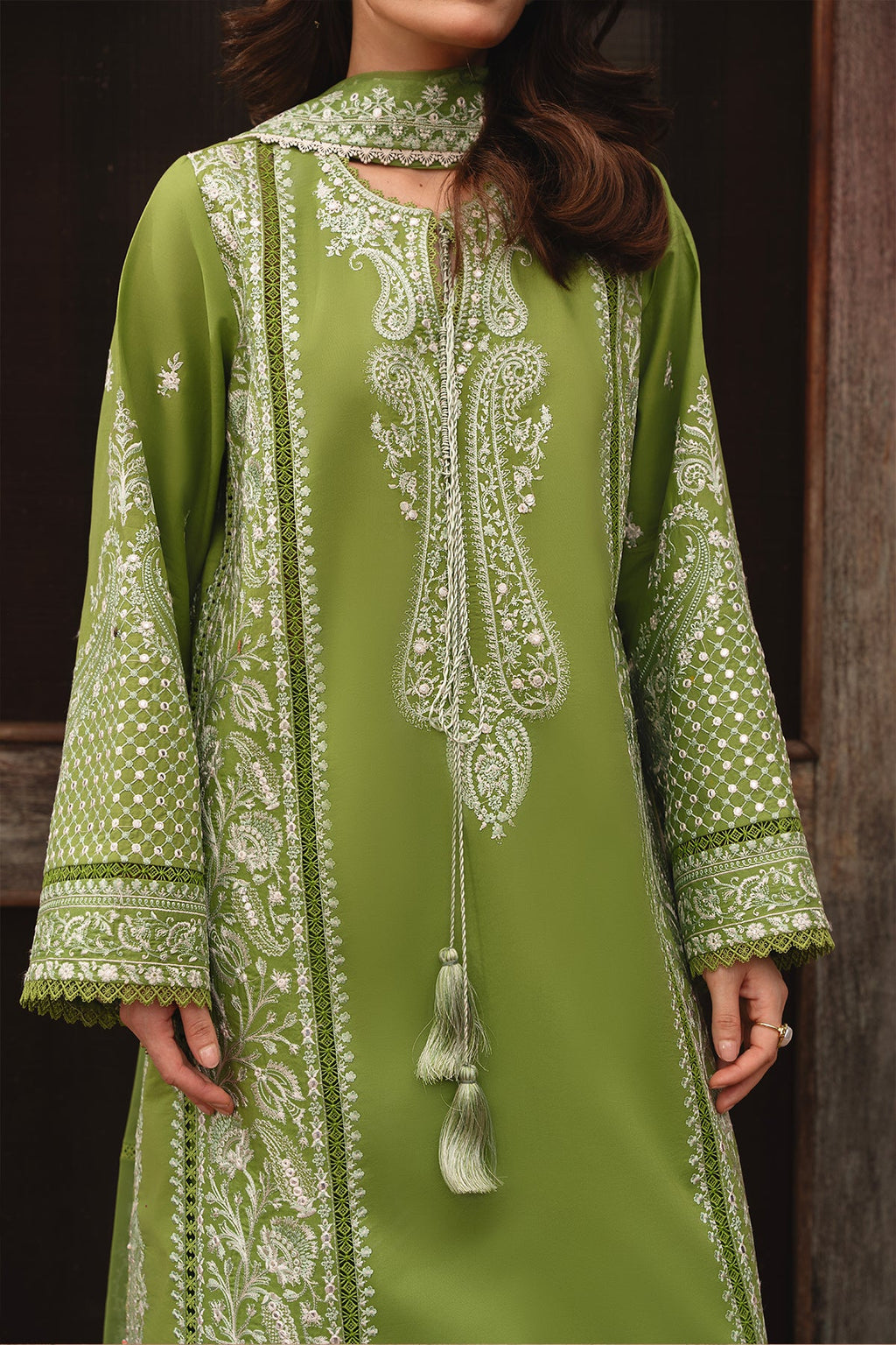 Green embroidered traditional outfit with white patterns on a wooden background