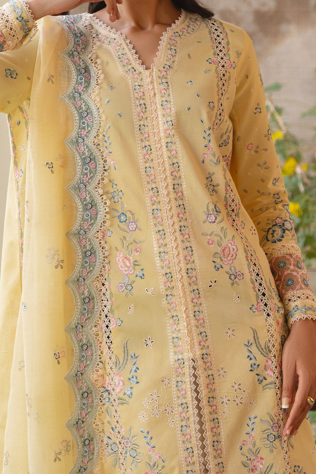 Yellow embroidered dress with floral patterns on a blurred natural background