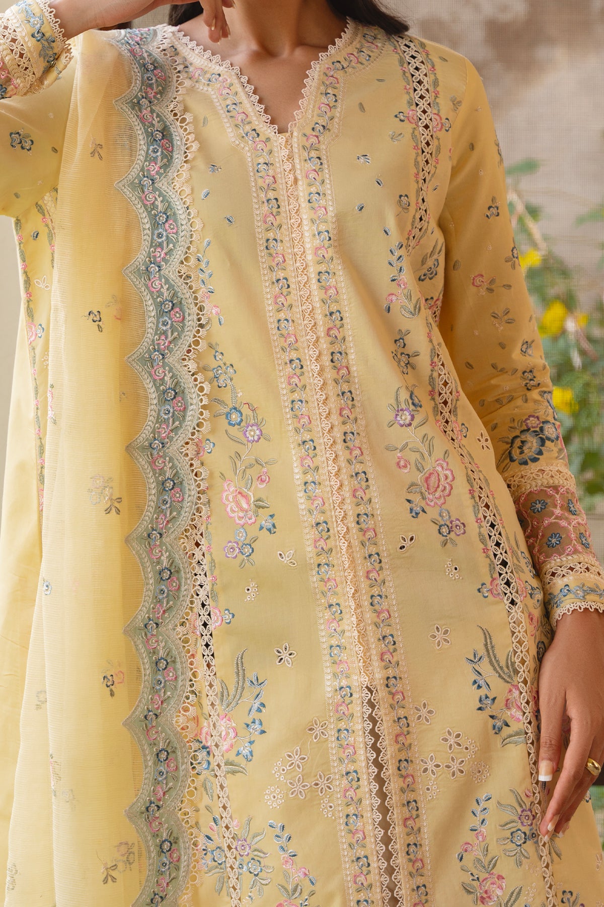 Yellow embroidered dress with floral patterns on a blurred natural background