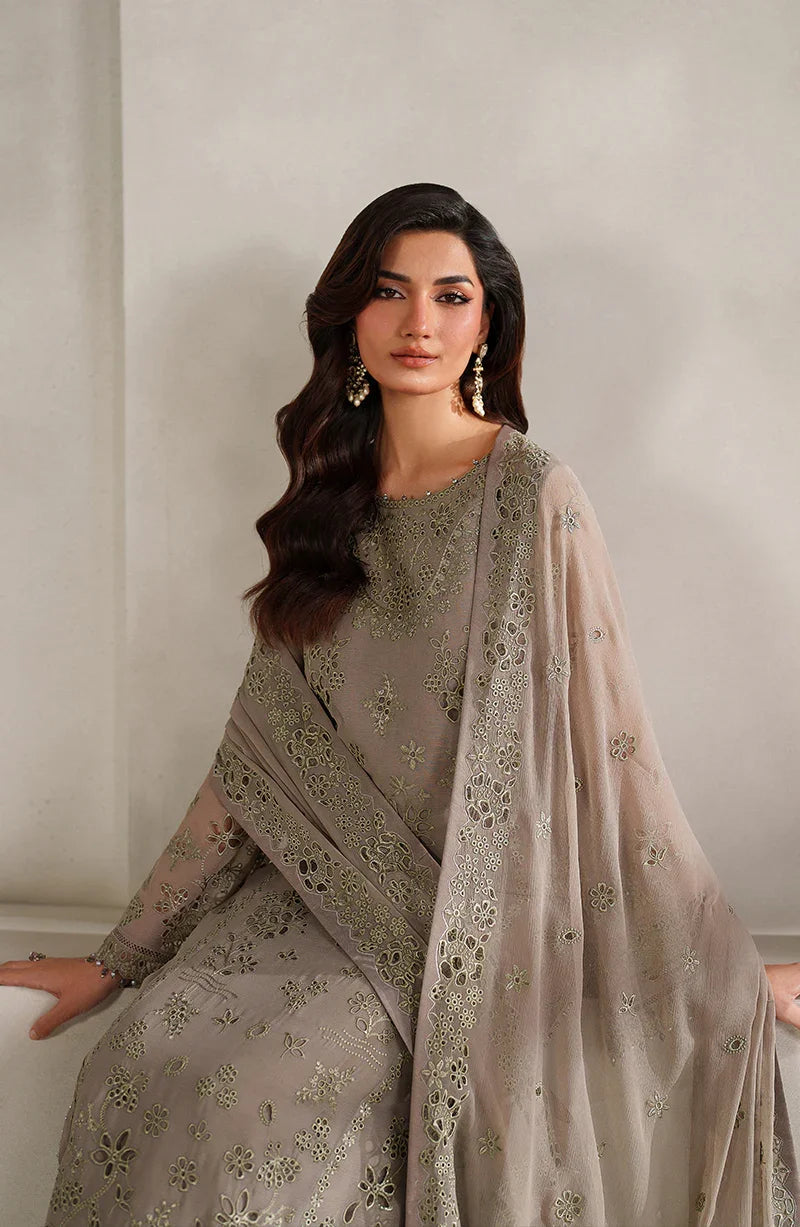 Woman wearing a gray embroidered outfit with a matching dupatta against a neutral background