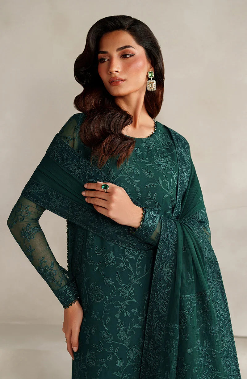 Woman wearing a green embroidered outfit with a plain background