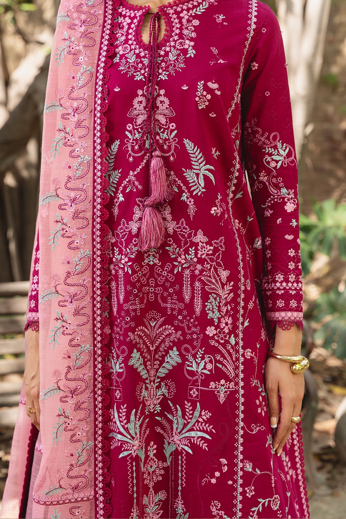 Pink embroidered traditional outfit with intricate patterns in a natural setting