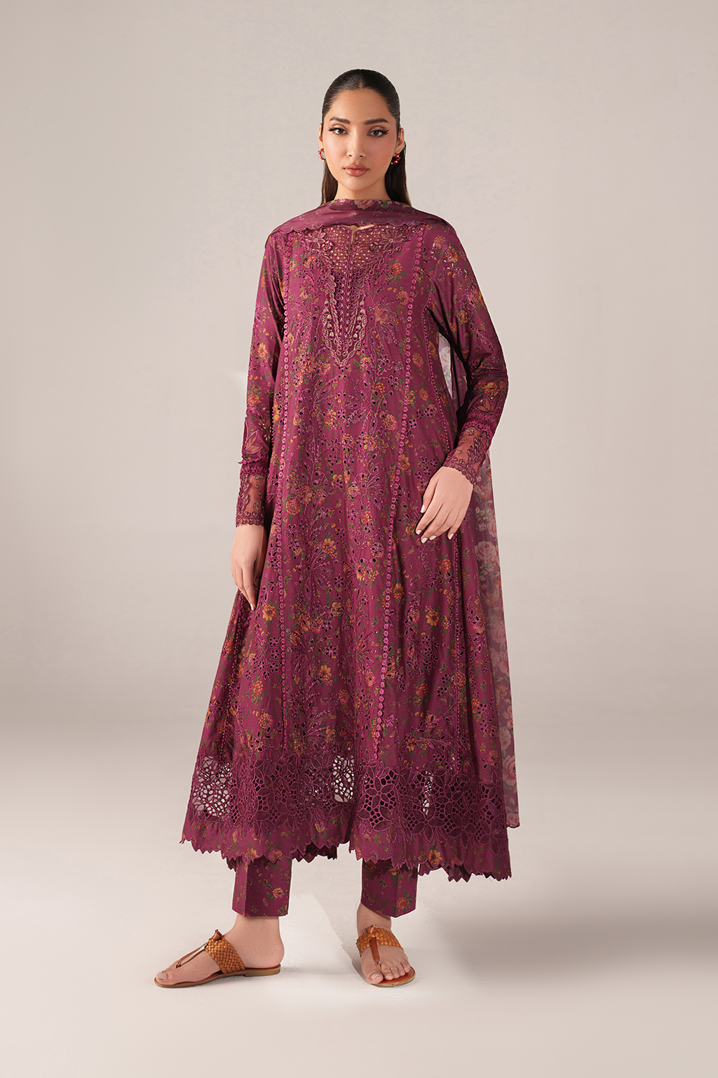 Woman wearing a maroon embroidered traditional outfit on a light gray background