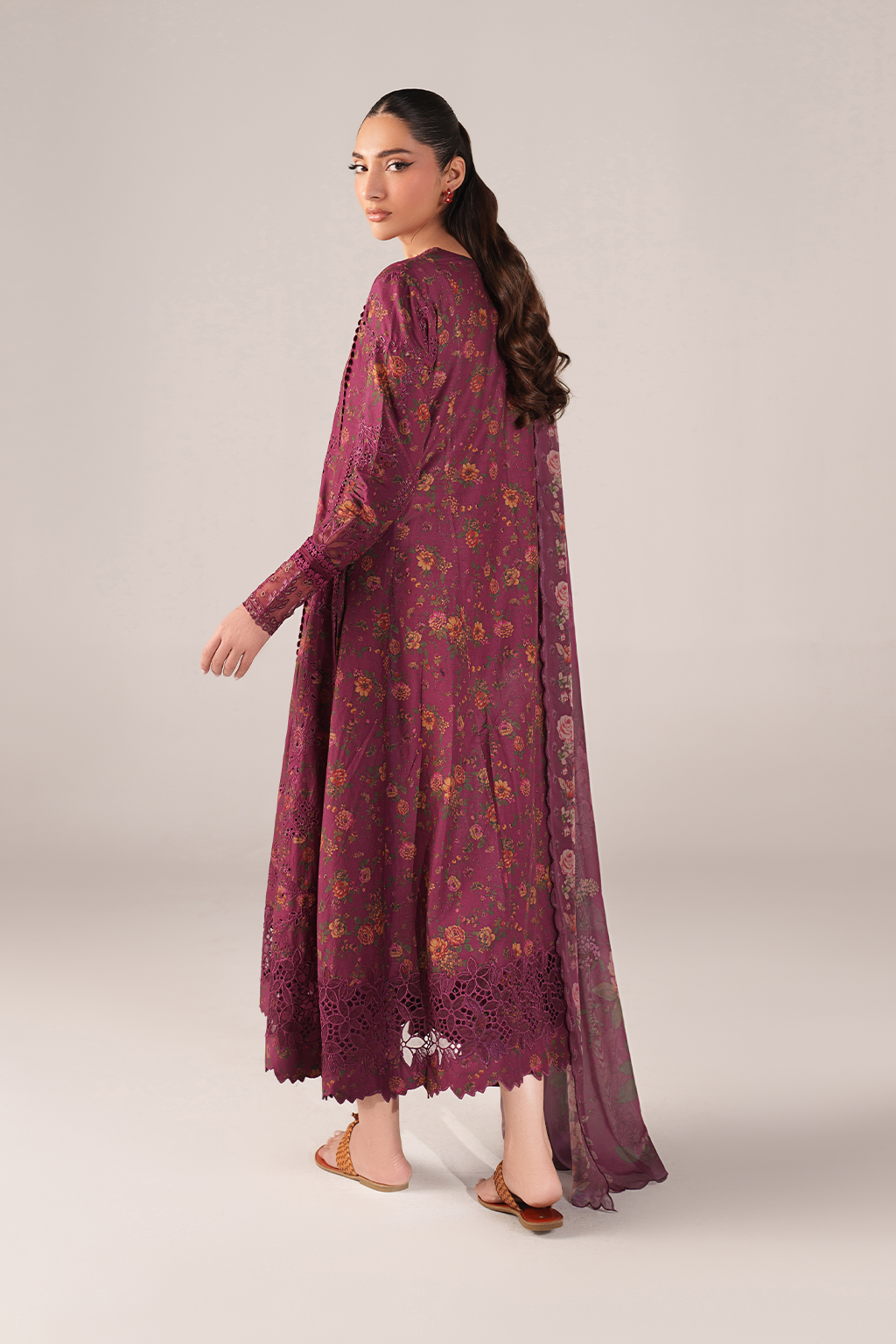 Woman wearing a long, burgundy floral dress on a light gray background