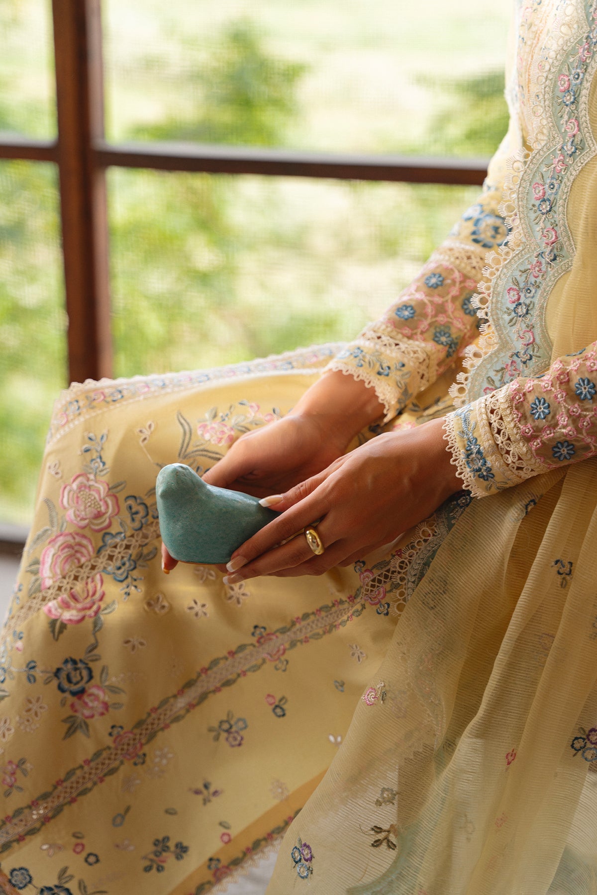 Person wearing a floral dress holding a small blue heart-shaped object.