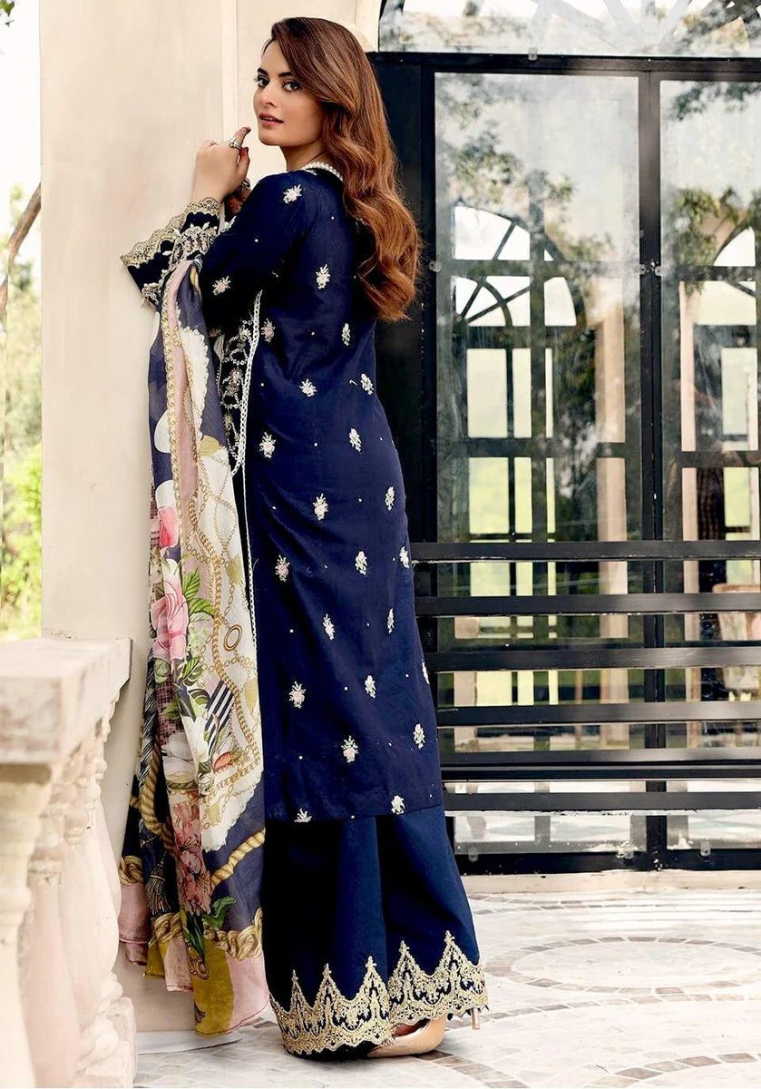A woman models a navy blue traditional outfit with silver embroidered motifs and a matching printed dupatta in an outdoor patio setting.