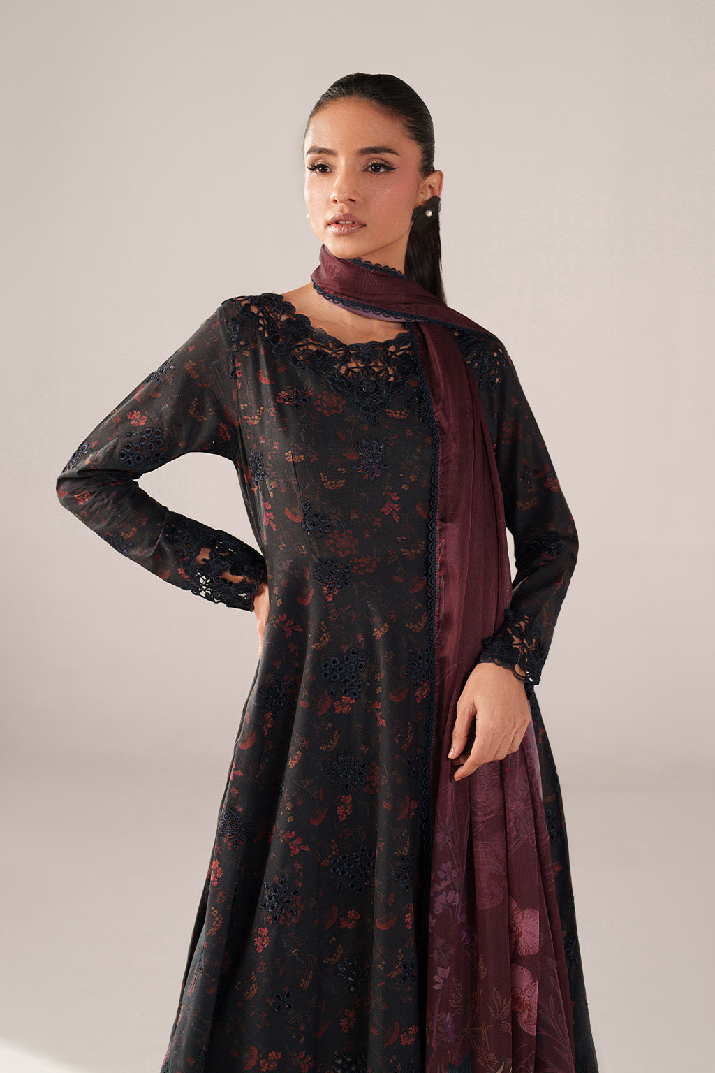 Woman wearing a black floral dress with a matching scarf on a light gray background