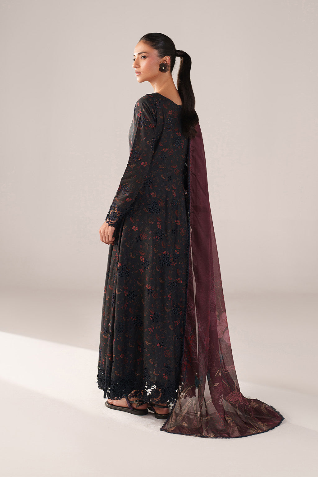 Woman wearing a black floral dress with a maroon dupatta on a white background
