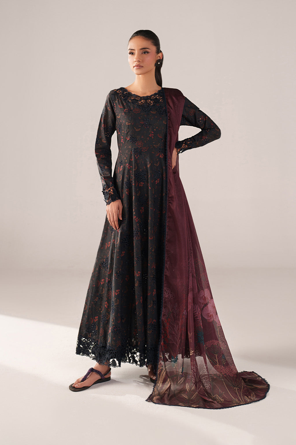 Woman wearing a black and red floral dress with a sheer maroon dupatta on a white background
