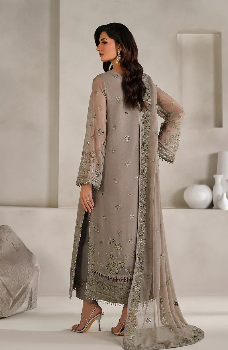 Woman wearing a gray embroidered outfit in a minimalistic room.