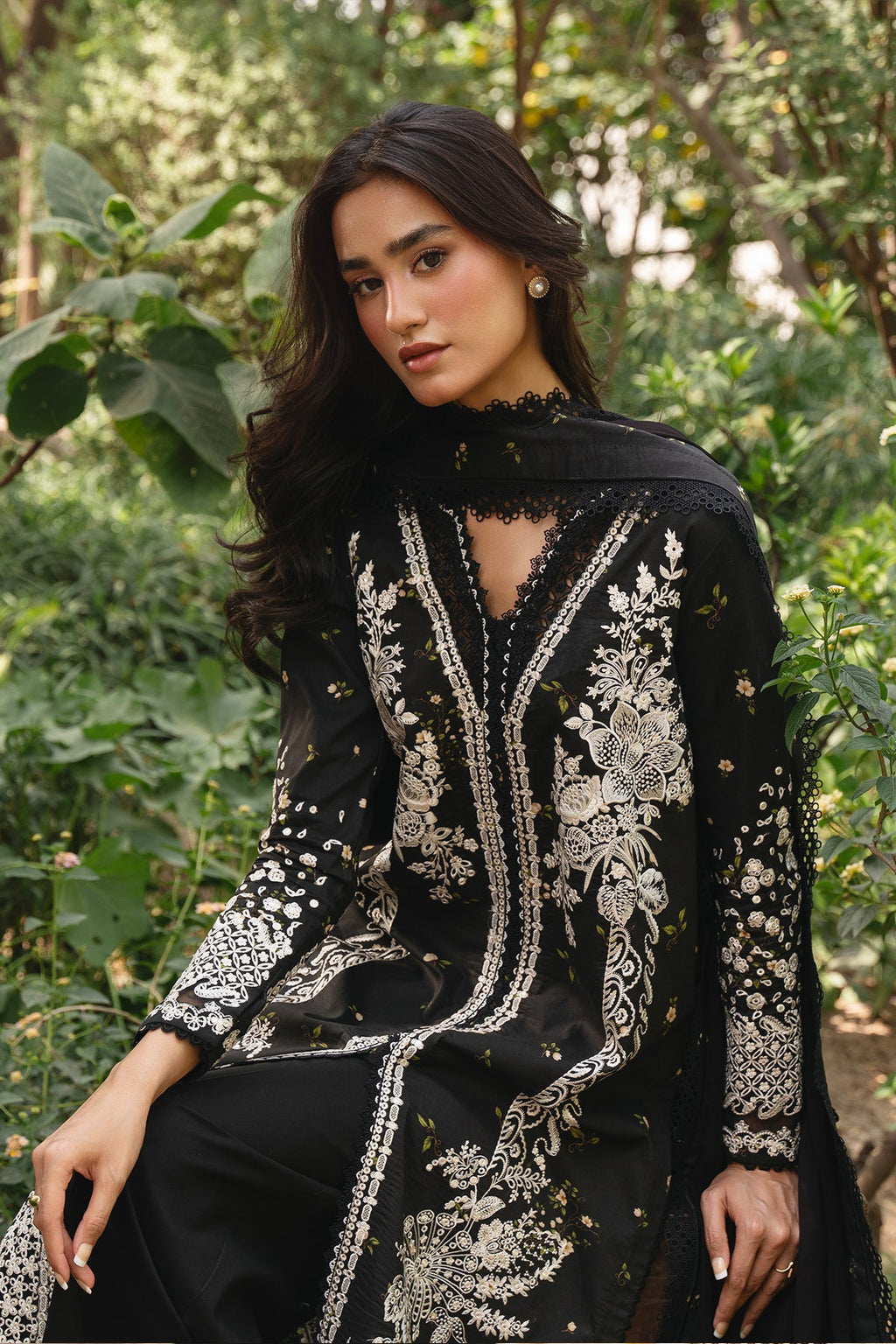 Woman wearing an embroidered black and white traditional outfit in a forest setting