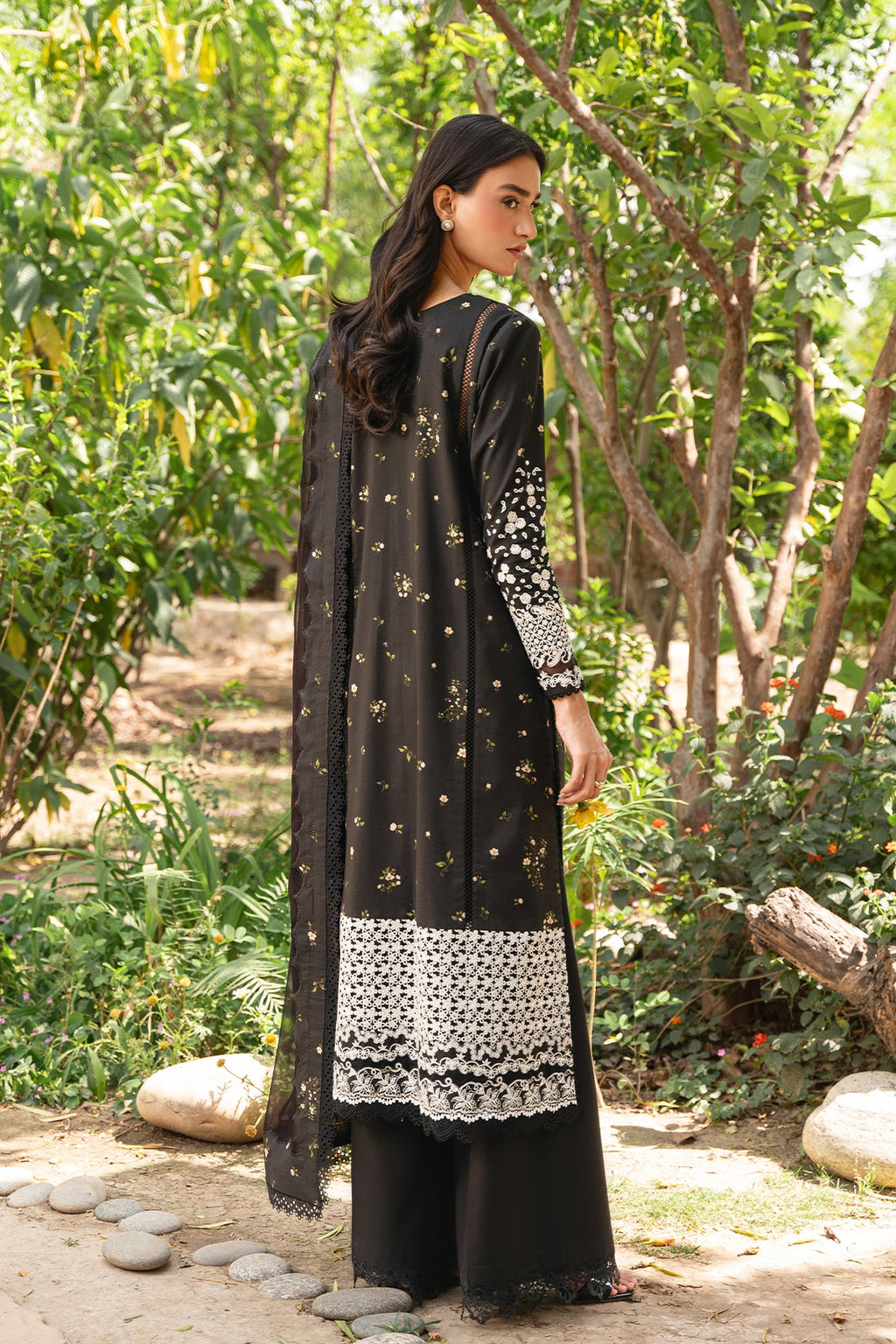 Woman wearing a black and white traditional outfit in a garden setting