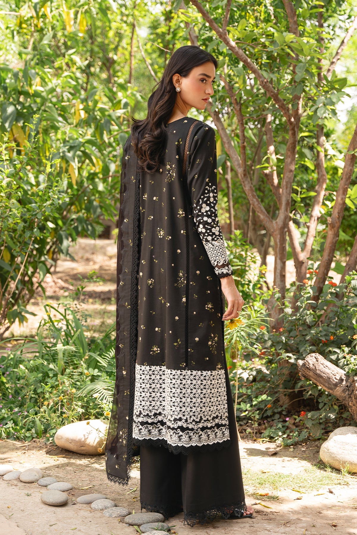 Woman wearing a black and white traditional outfit in a garden setting