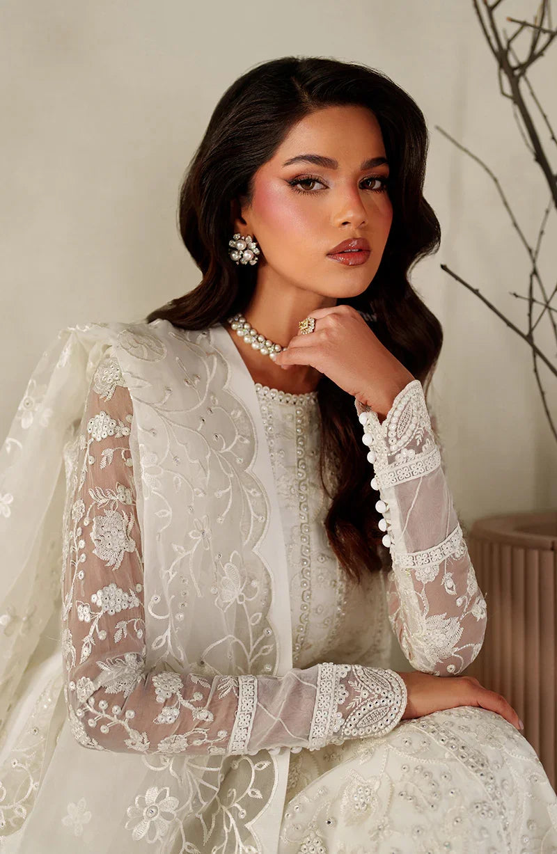 Woman wearing a white embroidered traditional outfit with a neutral background