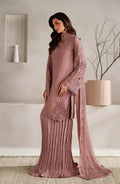 Woman wearing a pink saree with a matching blouse in a minimalistic room.