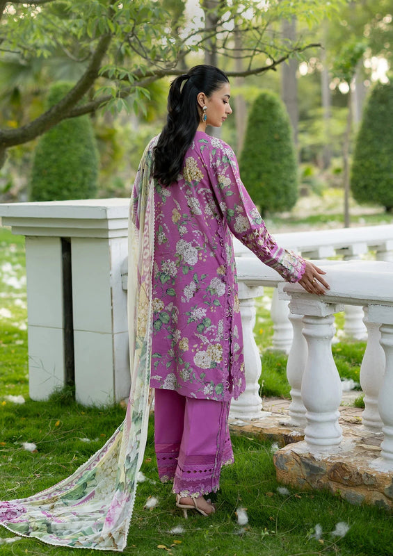Woman in a pink traditional outfit standing by a white railing in a garden.