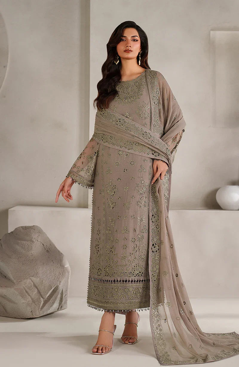 Woman wearing a beige embroidered traditional outfit with a matching dupatta in a minimalistic setting.