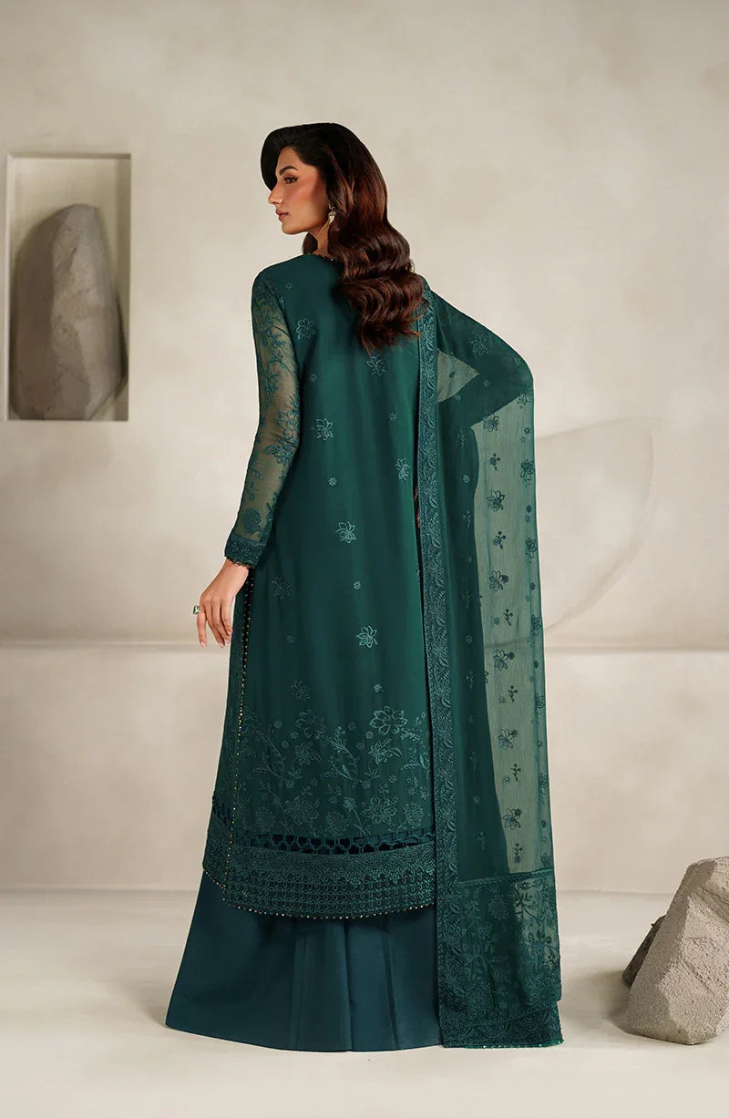 Woman wearing a teal traditional outfit with a matching dupatta in a minimalistic setting.