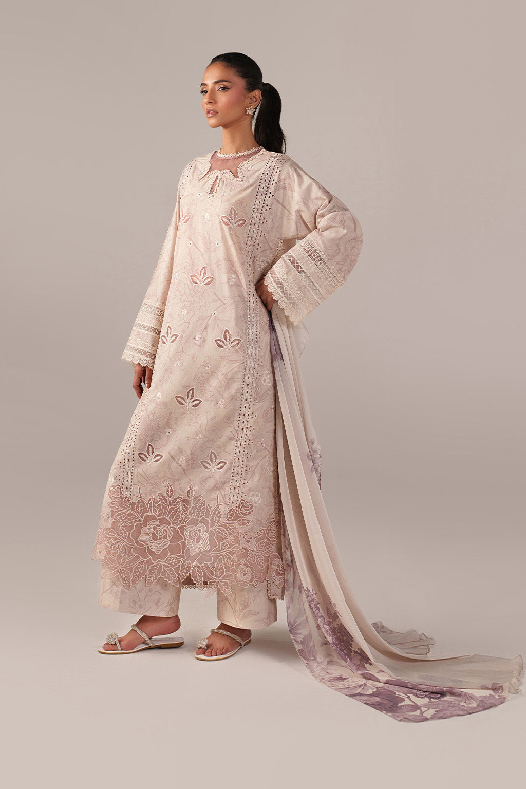 Woman wearing a light pink embroidered traditional outfit with a dupatta on a plain background