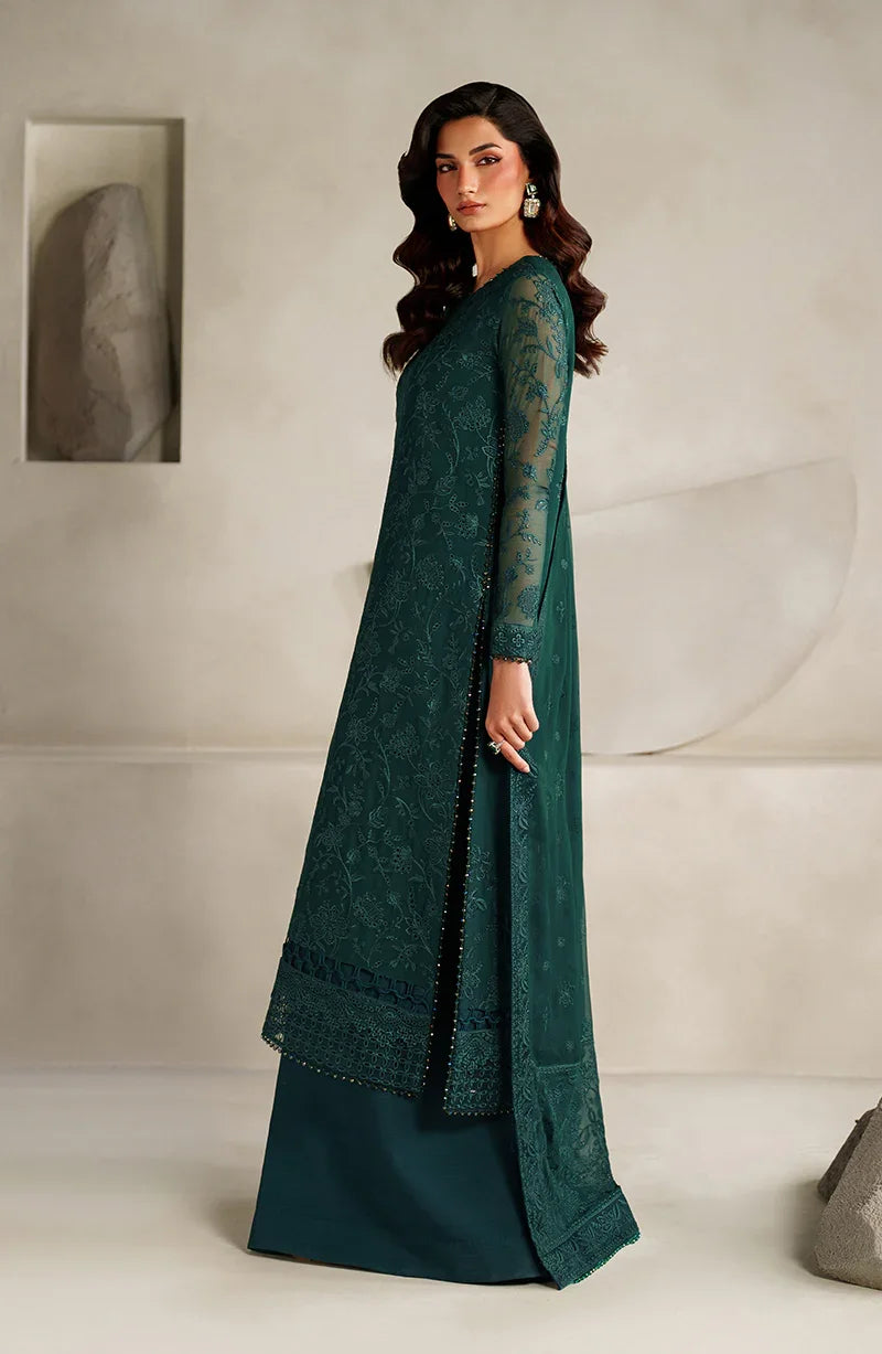 Woman wearing a green embroidered traditional outfit against a neutral background
