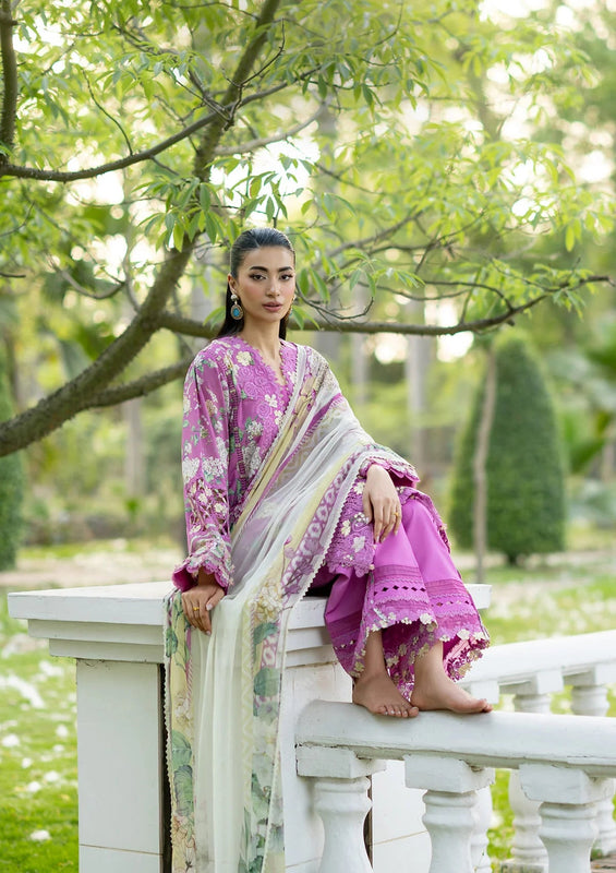 Woman in a pink saree sitting on a white railing in a garden.