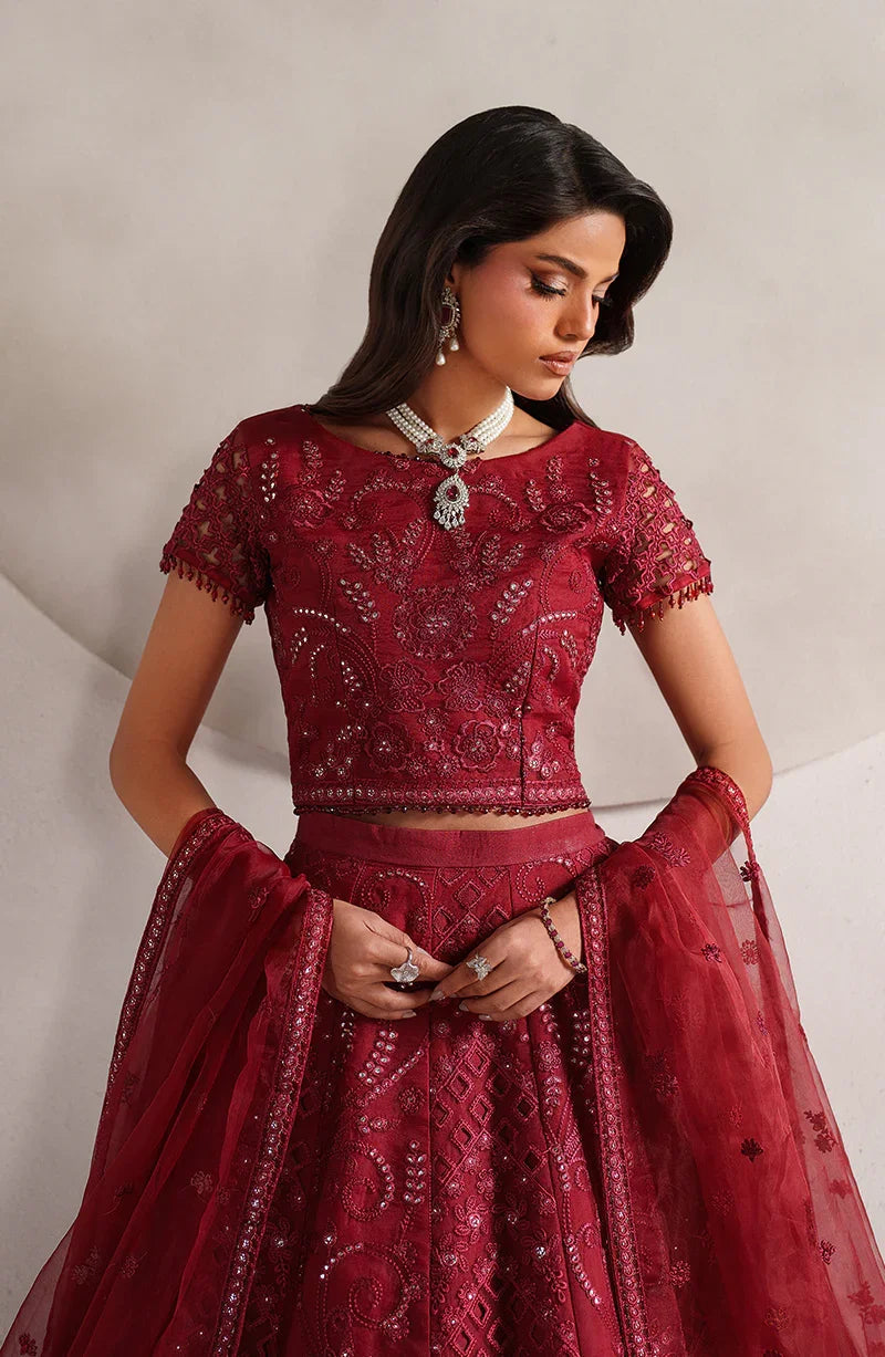 Woman wearing a red embroidered traditional outfit with a plain background