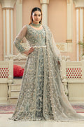 A woman wearing a gray maxi lehnga set with intricate embroidery and jewelry work, standing in a beautifully decorated room.