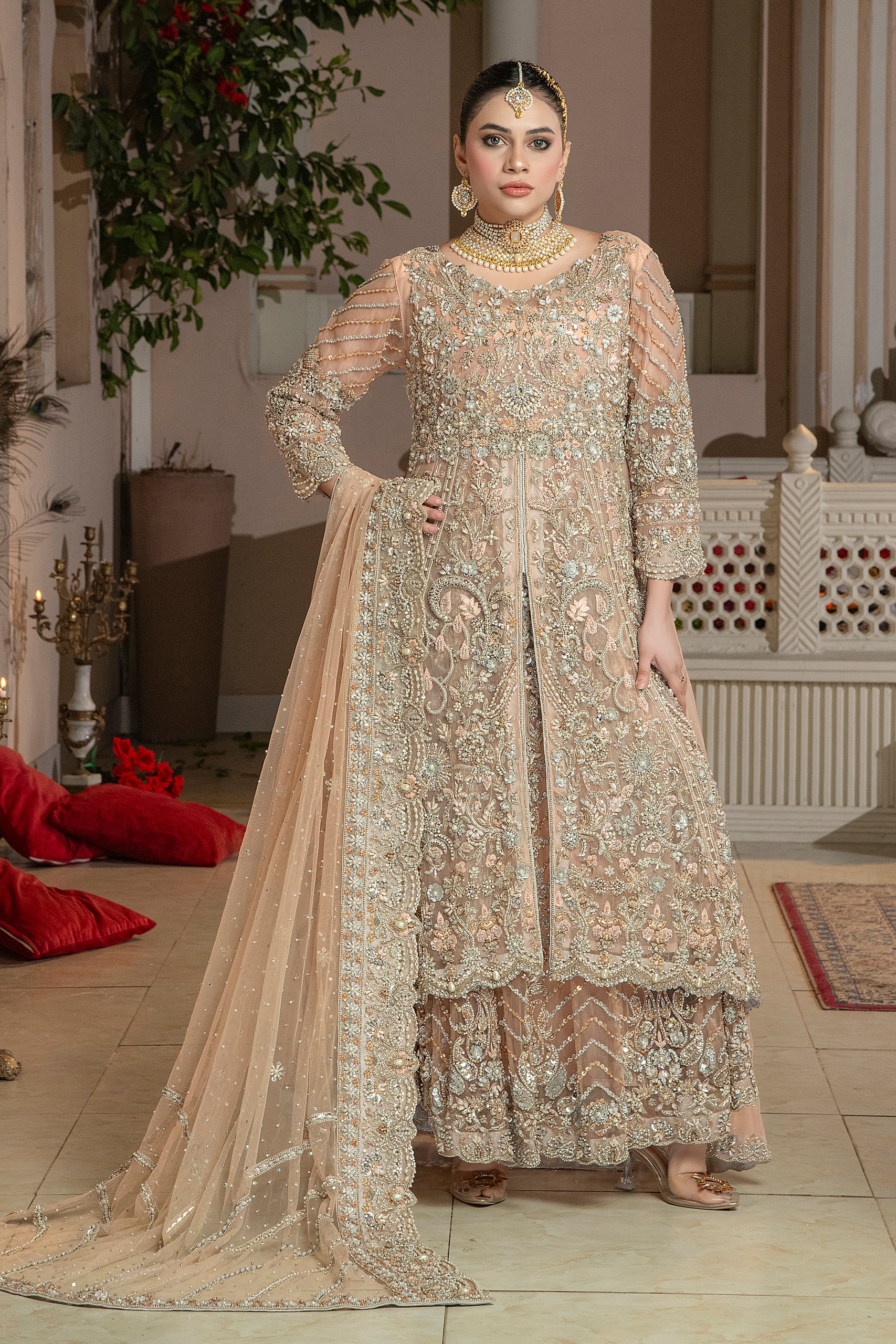 A woman wearing a traditional, peach-colored lehnga set with embroidery and a dupatta with a 4-inch embroidered mathapatti.