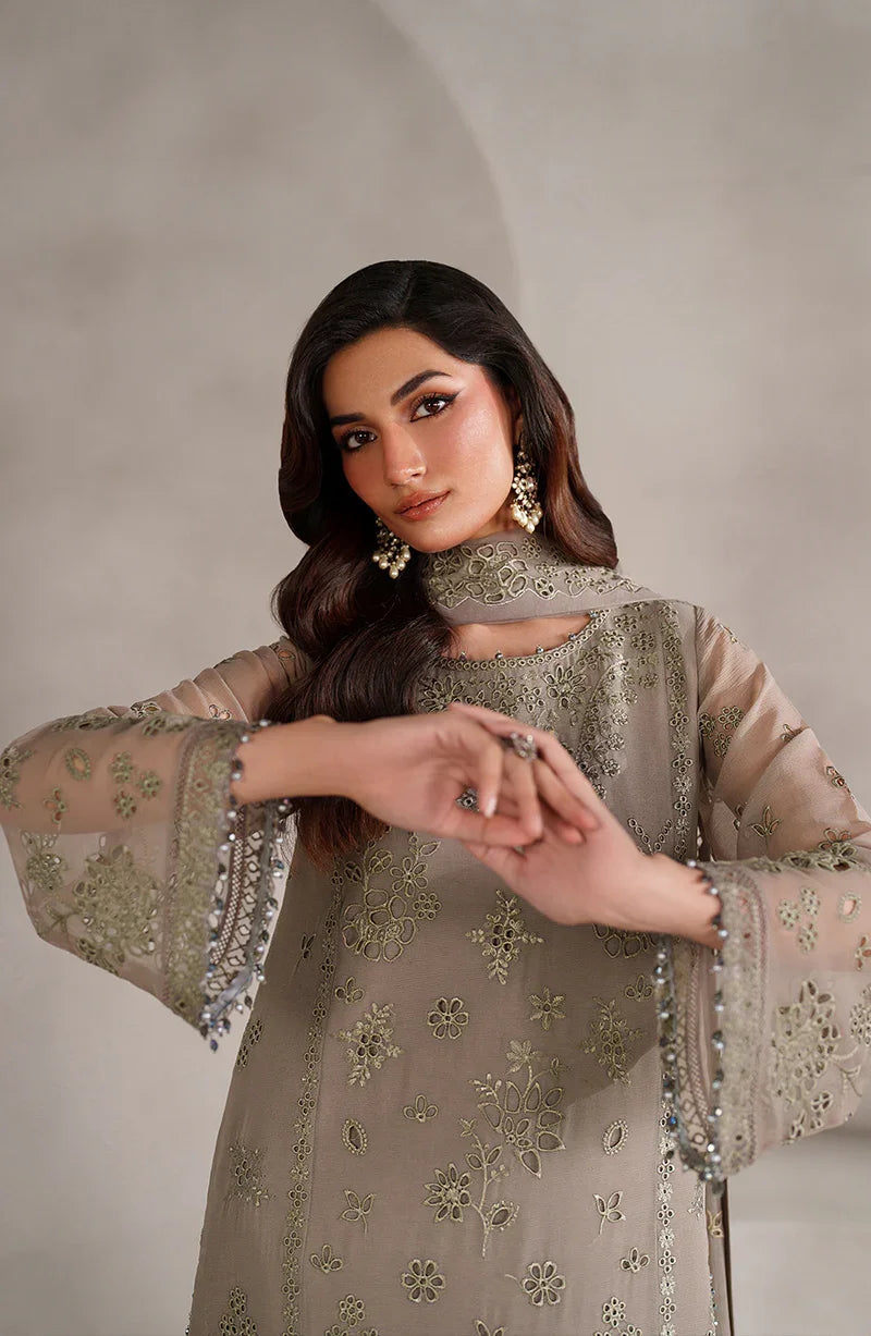 Woman wearing a beige embroidered traditional outfit against a neutral background