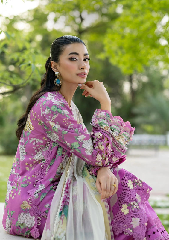 Woman in a pink floral outfit sitting outdoors with greenery in the background