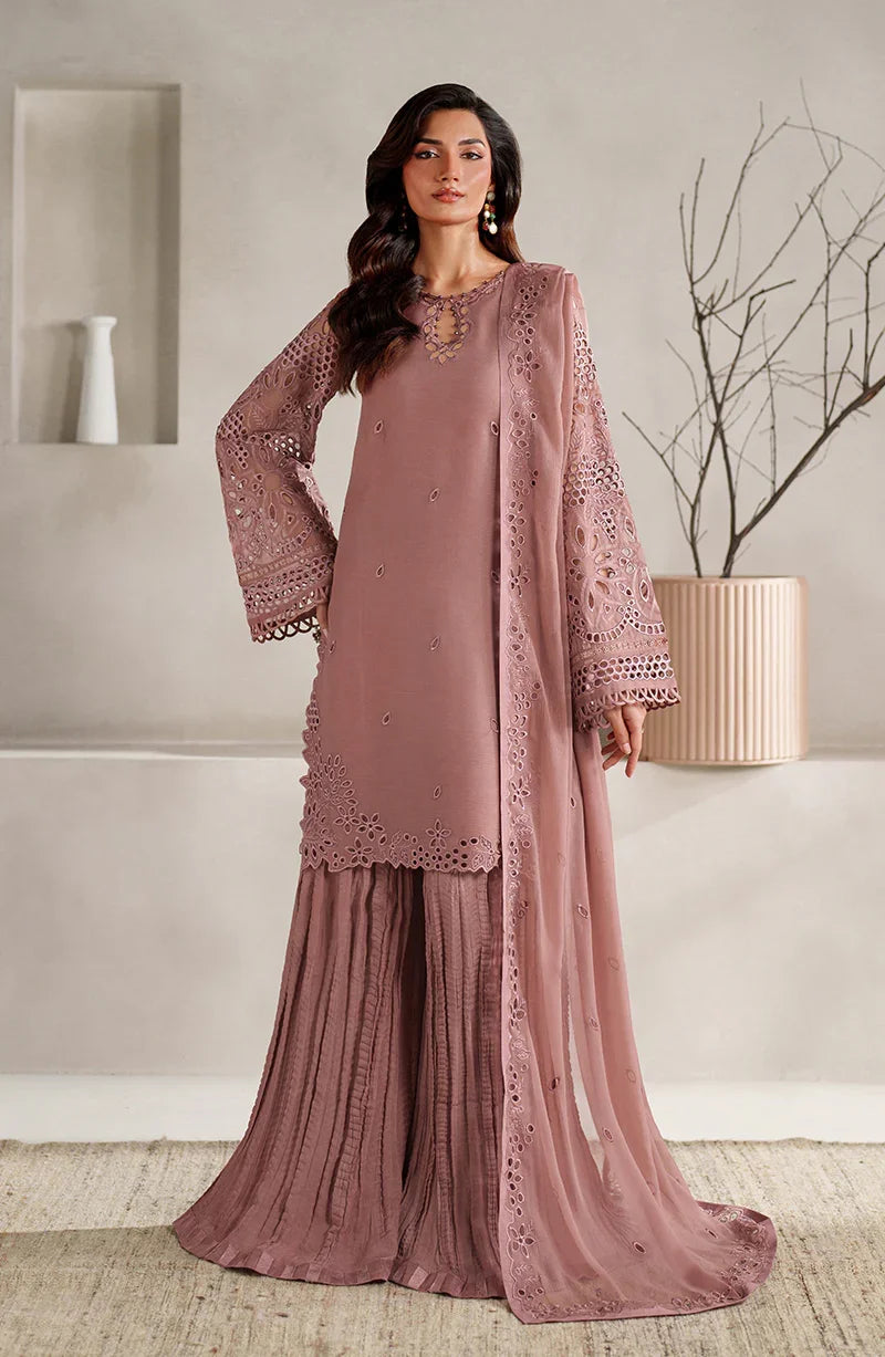 Woman wearing a mauve embroidered outfit in a minimalistic room.